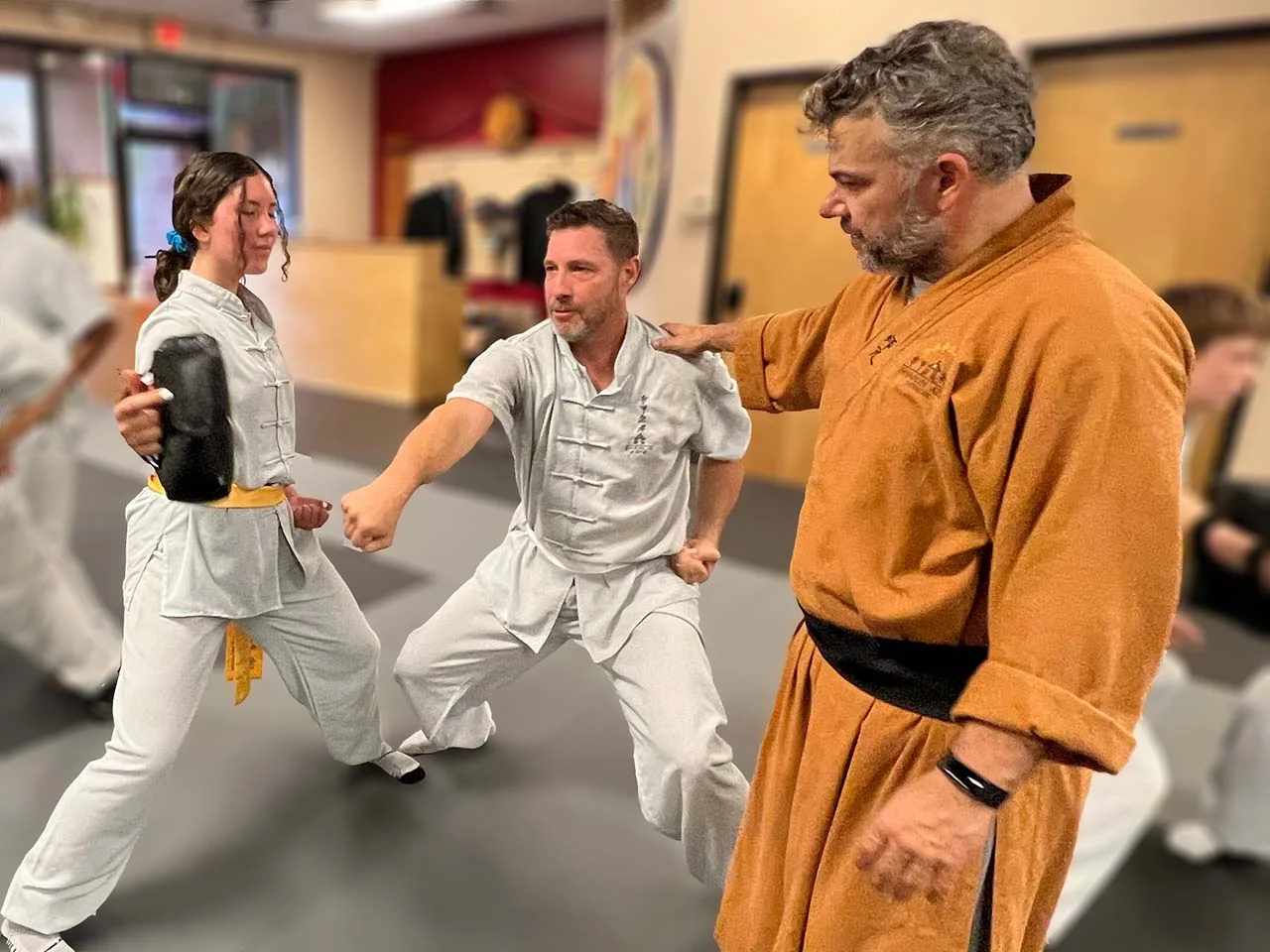 An instructor coaching two students in Kung Fu stance and technique